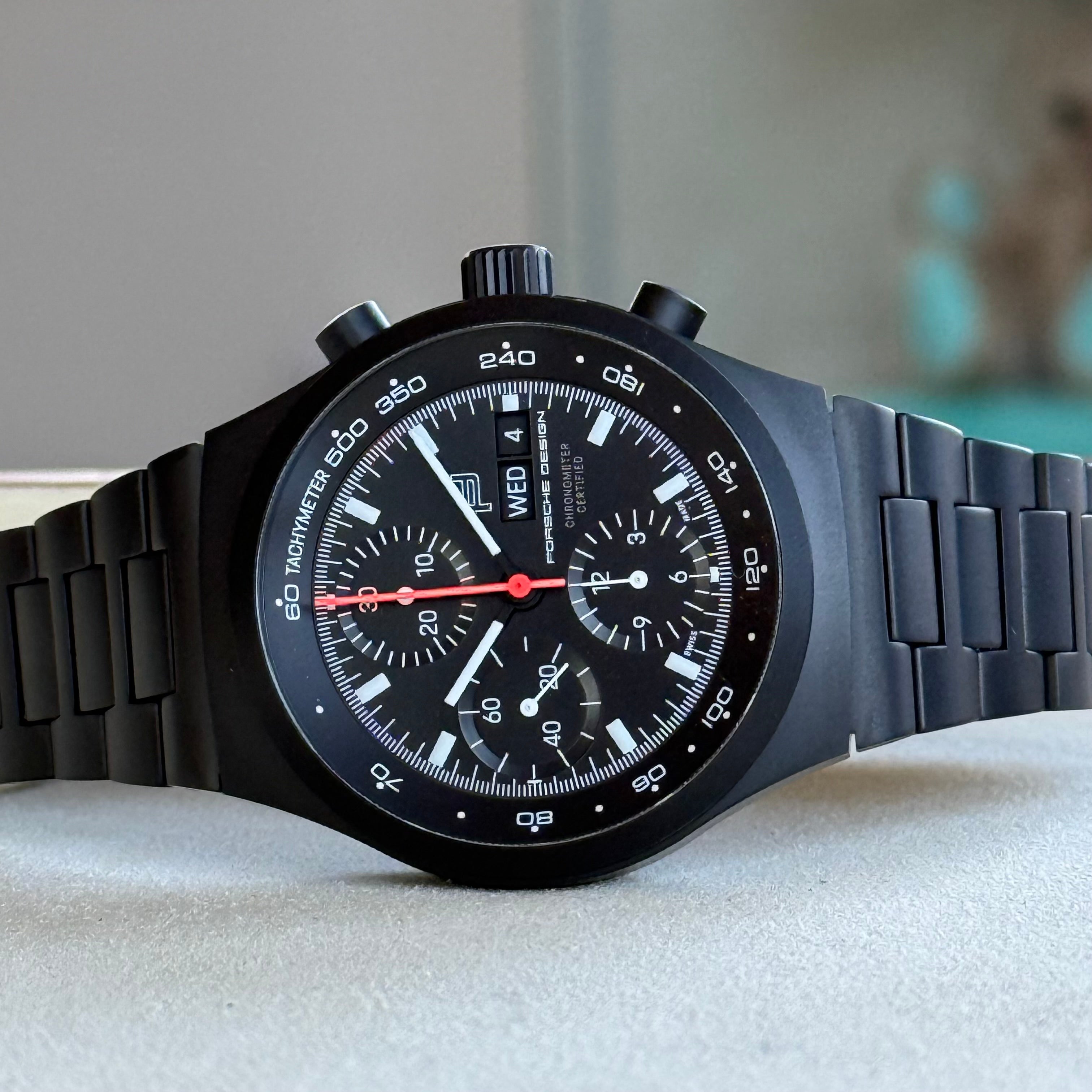 Porsche Design Chronograph 1 Rennsport Reunion 7 Edition Black Titanium Black dial with with white index hour markers and luminous black hands. Three black chronograph sub-dials. Day & date windows at 3 o’clock. Dial 6041.7.01.004.01.5